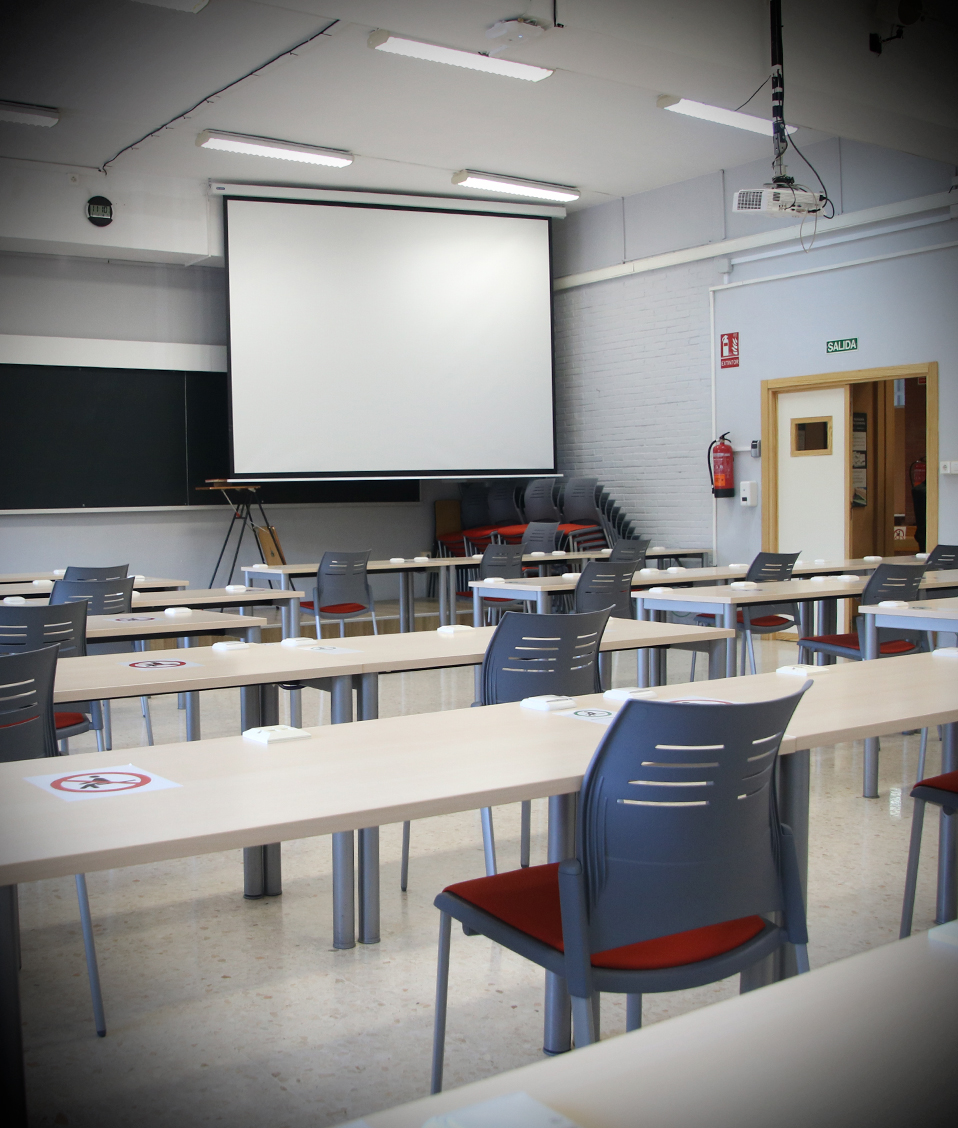 Aula de la Escuela Técnica Superior de Ingeniería de Edificación con mesas, una pizarra y un proyector